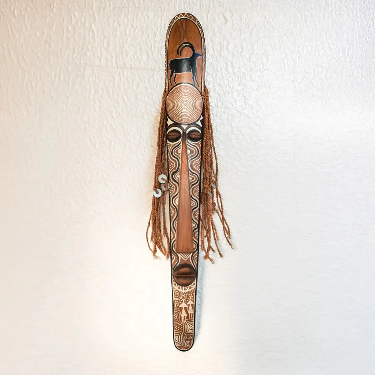 A tall hand-carved bamboo South Indian ritual mask featuring intricate tribal motifs, braided rope hair, and a sacred antelope totem